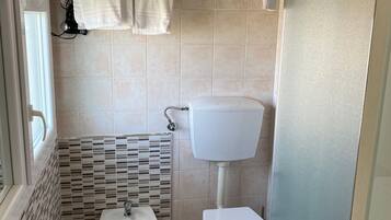 Een badkamer met een wastafel, bidet, toilet en een handdoekhouder met opgevouwen handdoeken.