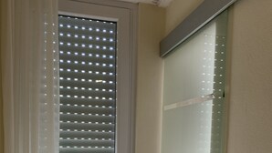 Une pièce dotée d’une porte-fenêtre coulissante, d’une chaise et d’un interrupteur fixé au mur.