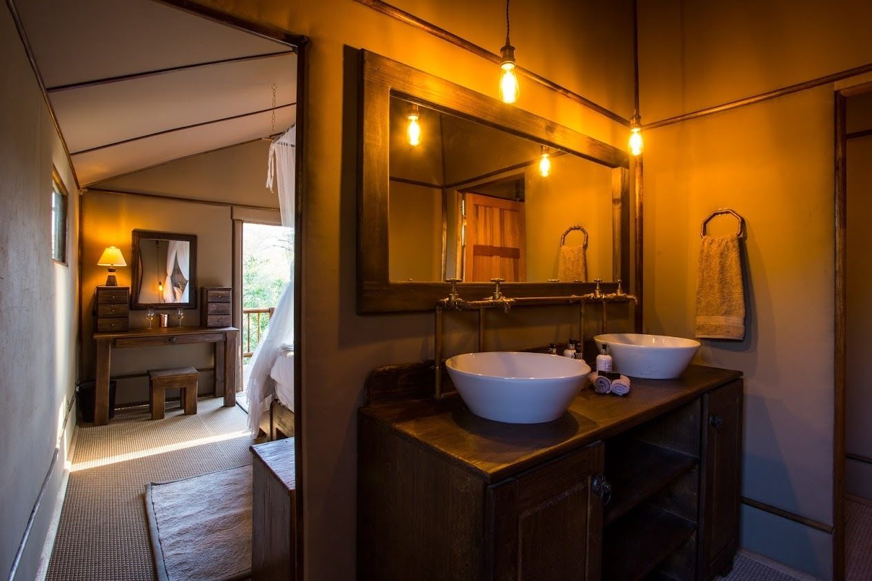 A bathroom with two sinks, a large mirror, and wooden cabinetry.