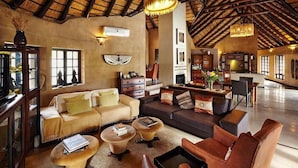 A spacious living area with a high ceiling, wooden beams, and a central seating arrangement. - Vuyani Safari Lodge (Hoedspruit)