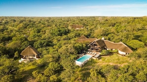 A remote lodge with thatched-roof cabins surrounded by dense forest. - Vuyani Safari Lodge (Hoedspruit)