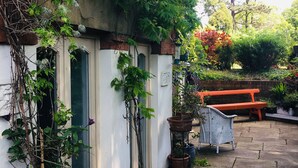 A courtyard with a white building, a large tree, and a wooden bench. - OYO Cornerstone Manor Hotel (Sale)