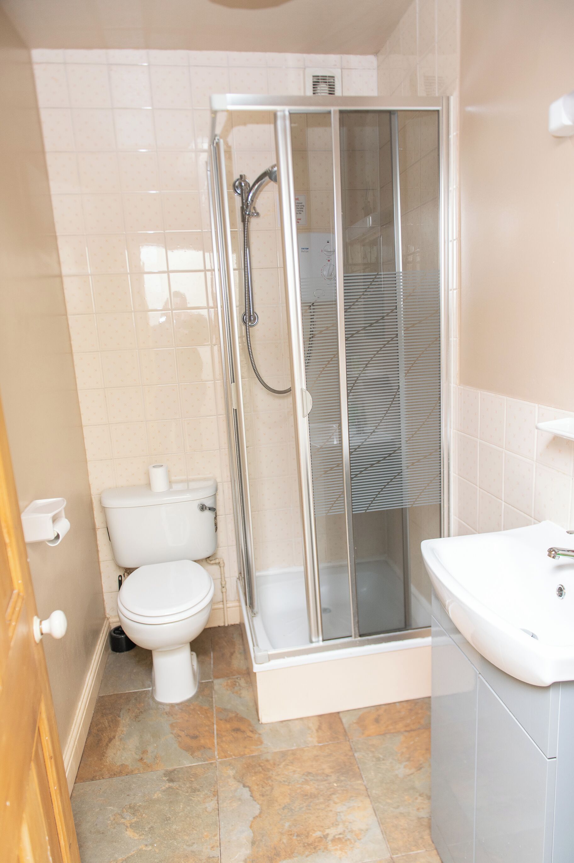 A bathroom with a glass-enclosed shower, a toilet, and a sink.