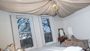 A bedroom with a large bed, a dresser, a mirror, and a window with a view of trees. - OYO Cornerstone Manor Hotel (Sale)