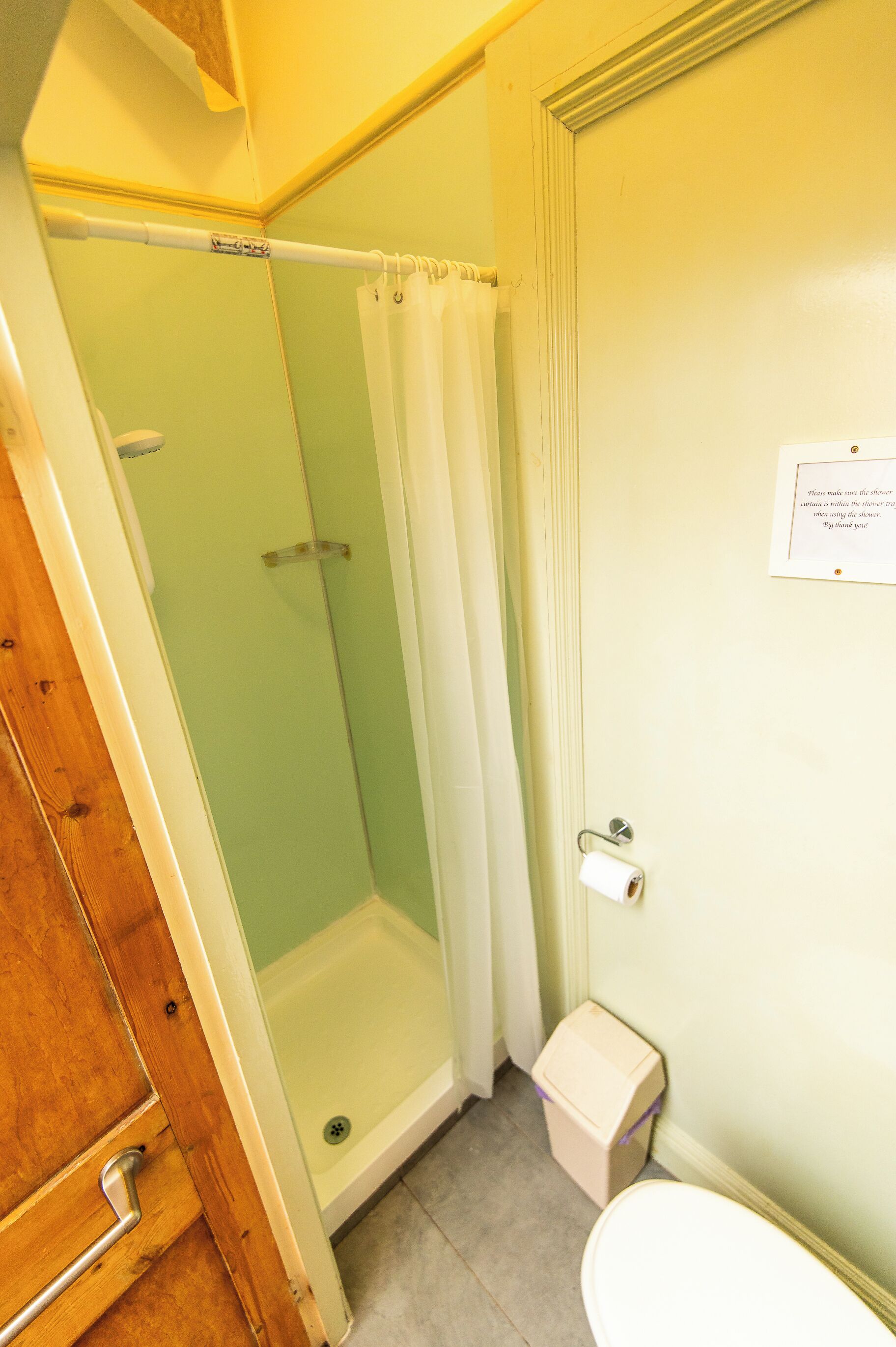 Ein Badezimmer mit Dusche, Toilette und einer Tür mit einem Schild.