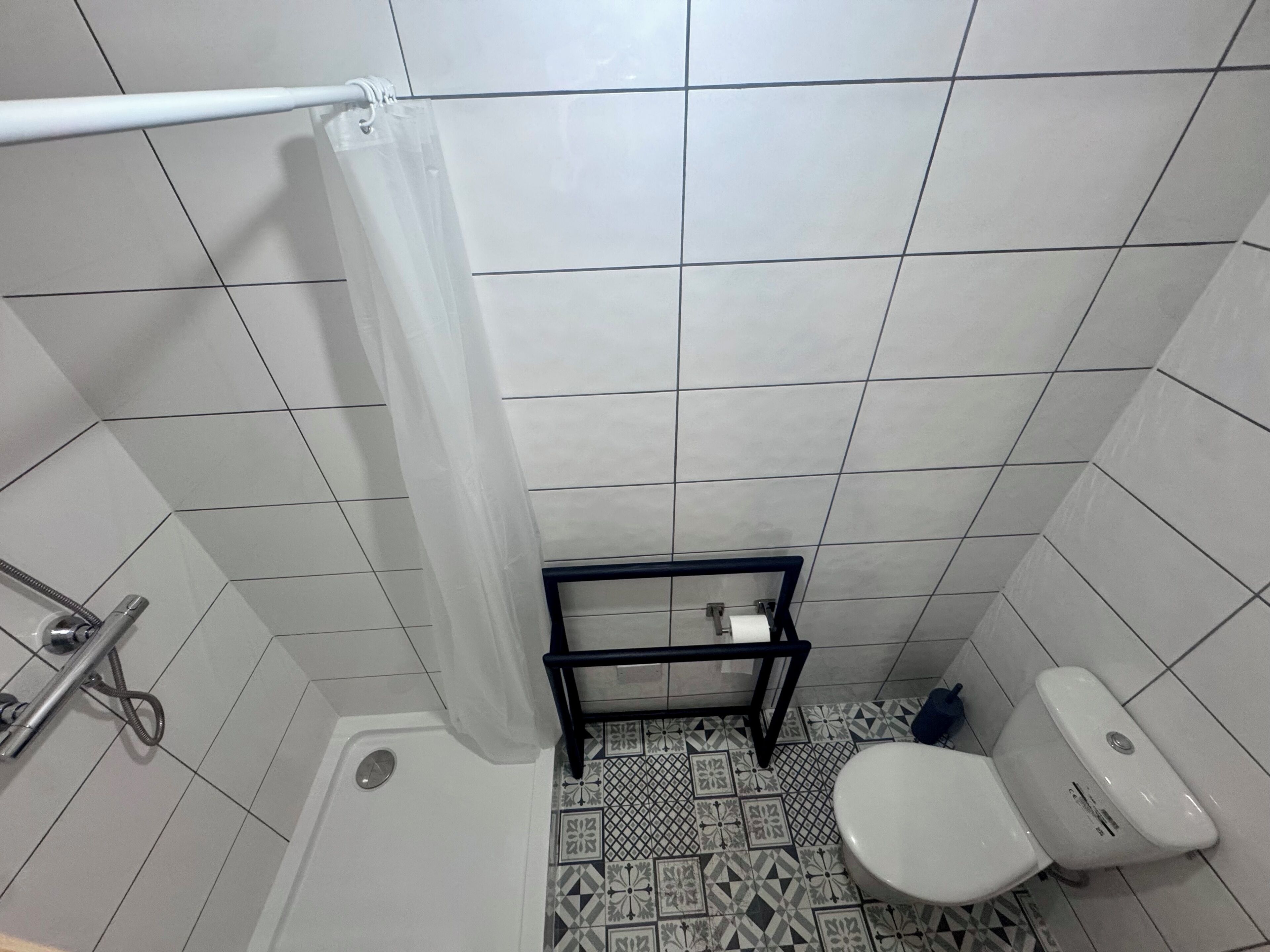 A small bathroom with a shower, toilet, and a sink with a hose.