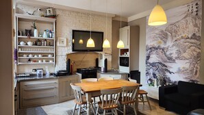 A kitchen with a dining area, a flat-screen TV, and a traditional Chinese mural. - OYO Cornerstone Manor Hotel (Sale)