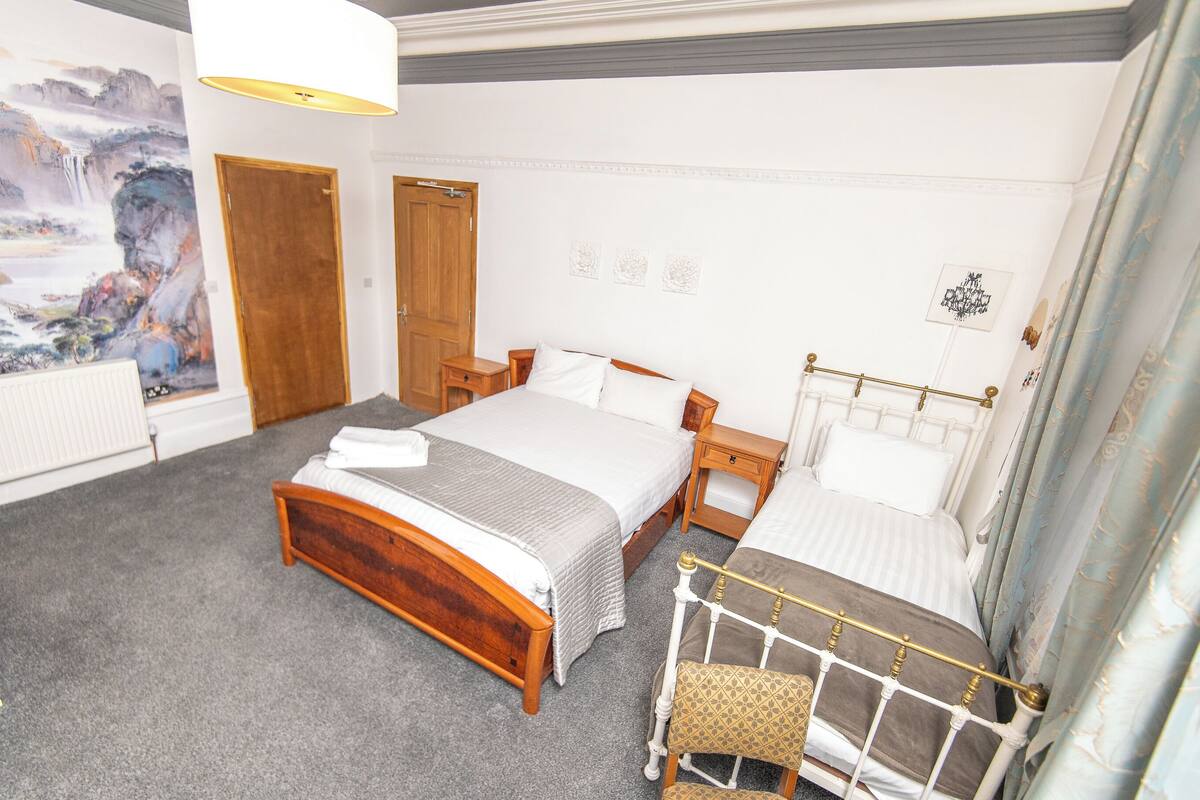 Ein Schlafzimmer mit zwei Betten, einem Holzkopfende, einem Nachttisch und einem großen Bild an der Wand.