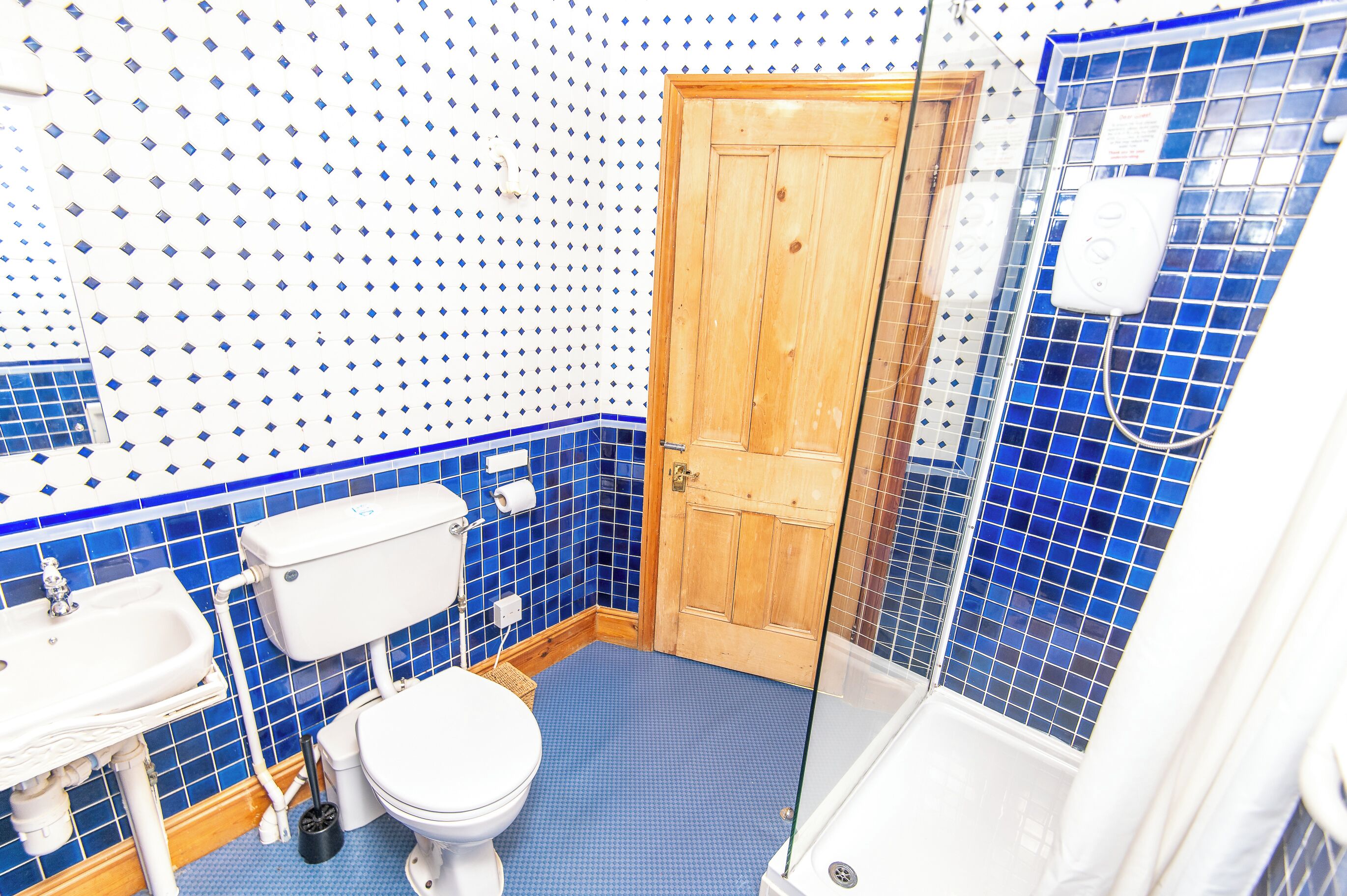 A bathroom with a toilet, sink, and shower area.