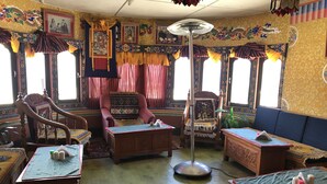 Una habitación tradicional con sofá, sillones, una mesa de madera y un ventilador de pie.