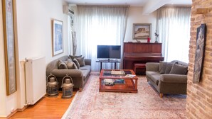 Una sala de estar con sofá, mesa de centro, televisor, piano y chimenea.