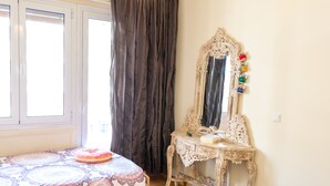 Un dormitorio con cama, cómoda, espejo y ventana con cortinas.