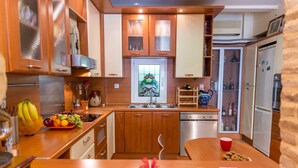 Una cocina moderna con armarios de madera, un refrigerador de acero inoxidable, un lavavajillas y un frutero en la encimera.