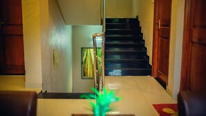 A staircase with a handrail, wooden doors, and a tiled floor. - Royal Paradise Hotel (Alibag)
