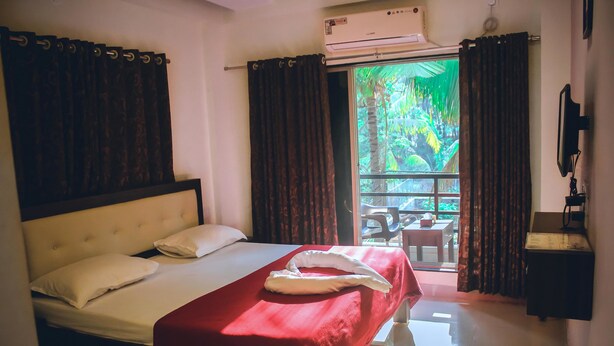 A hotel room with a bed, a red blanket, a white pillow, and an air conditioning unit. - Royal Paradise Hotel (Alibag)