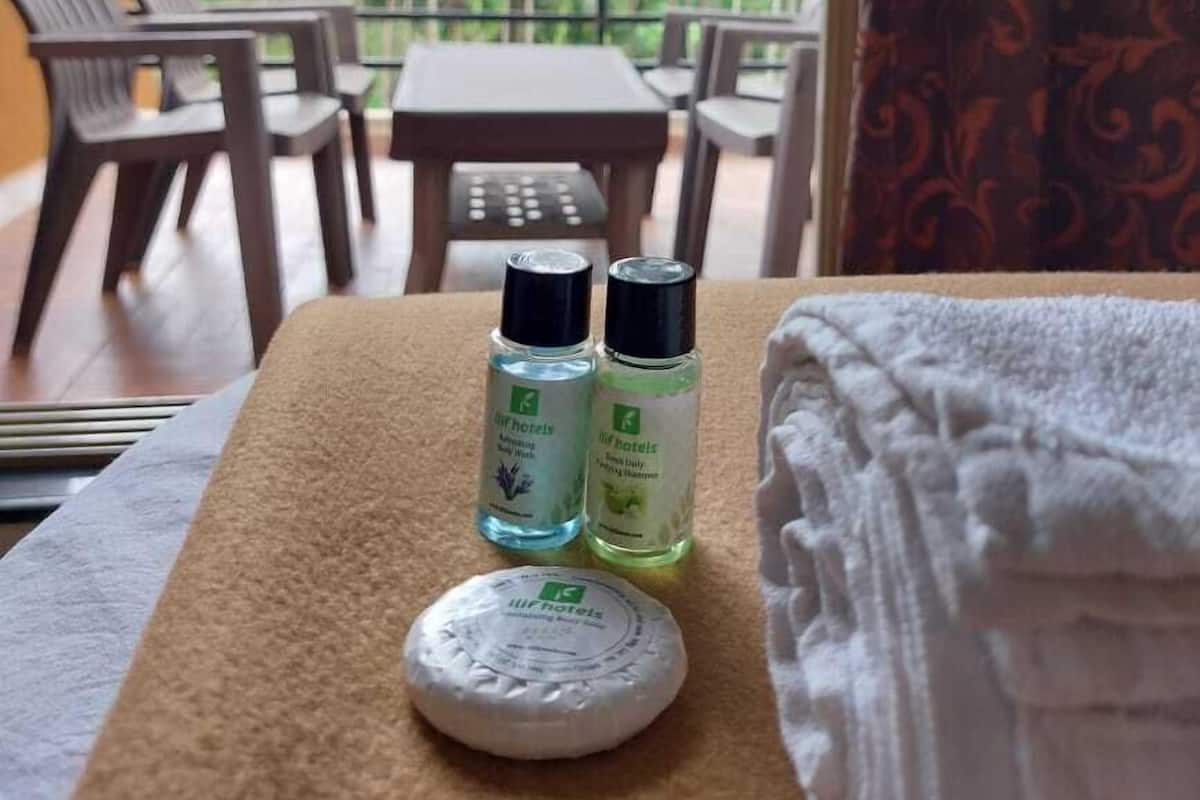 A balcony with a view of lush greenery, a table with two bottles of toiletries, and a round soap dish.