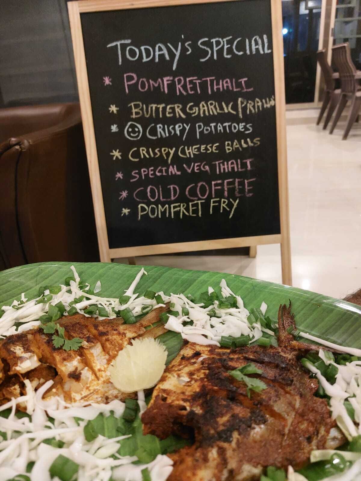A menu board listing today's specials including Pommfret Thali, Butter Garlic Prawns, Crispy Potatoes, Crispy Cheese Balls, Special Veg Thali, Cold Coffee, and Pommfret Fry.