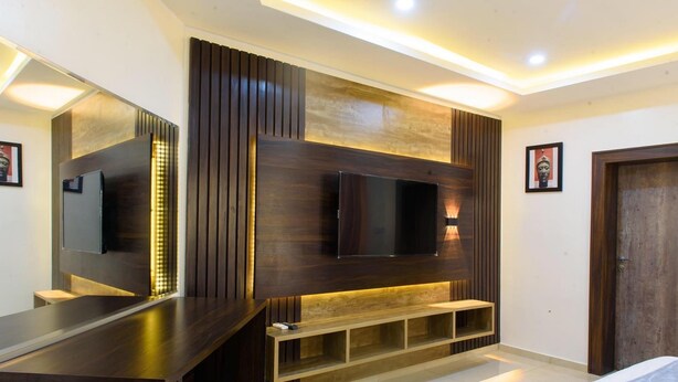 A modern bedroom with a large bed, a built-in TV, and a wooden entertainment unit. - Ambience Hotel and Resorts (Lagos)