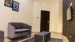 A modern lobby with a grey sofa, a dark wooden door, and a patterned wall. - Ambience Hotel and Resorts (Lagos)