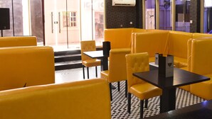 A restaurant with yellow booths and black tables, a tiled floor, and an air conditioning unit on the wall. - Ambience Hotel and Resorts (Lagos)