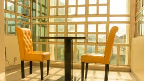 A room with two yellow upholstered chairs and a black table, large windows, and a tiled floor. - Ambience Hotel and Resorts (Lagos)