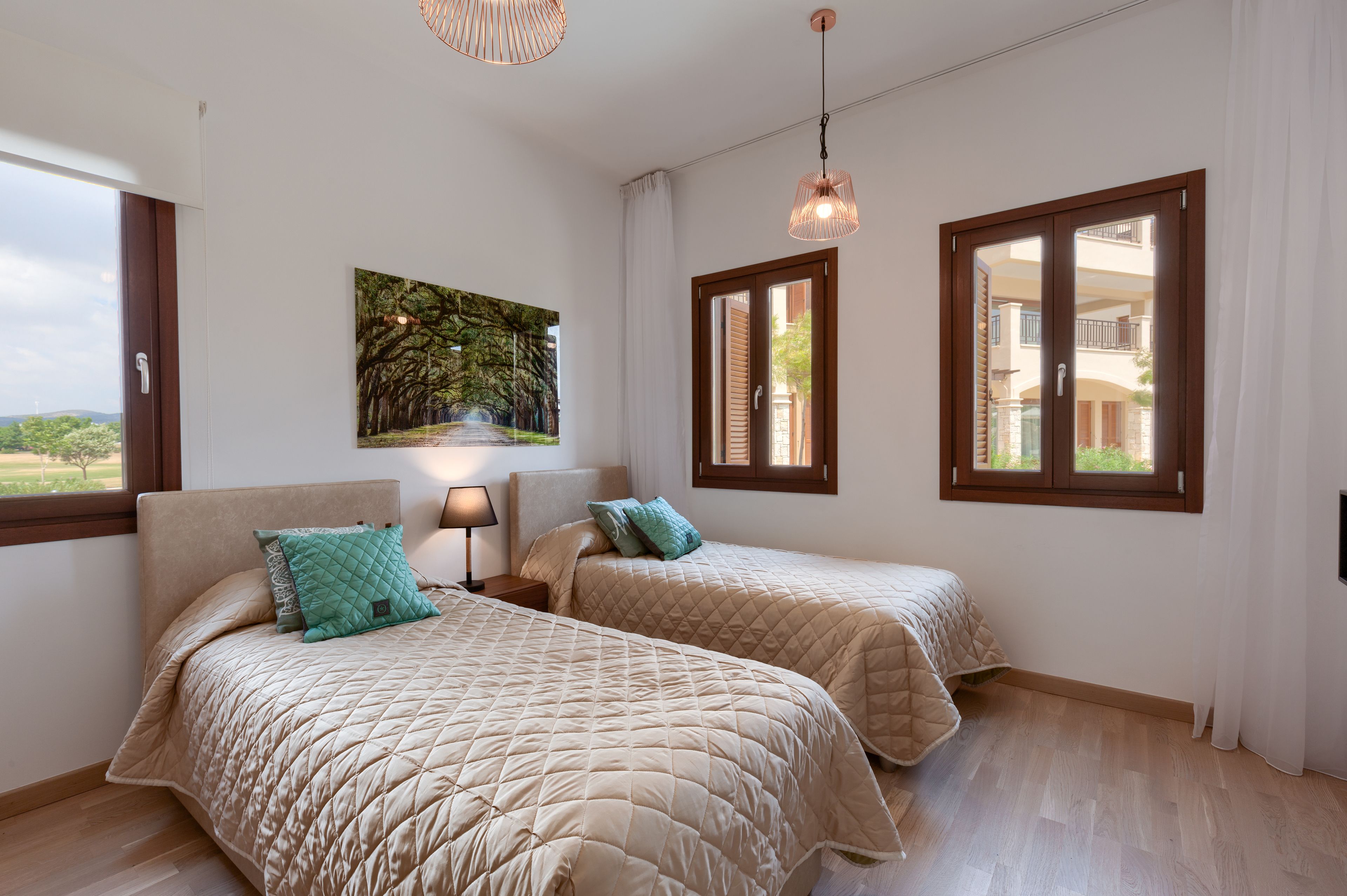 Un dormitorio con dos camas, una mesita de noche, una lámpara, un cuadro y una ventana con contraventanas.