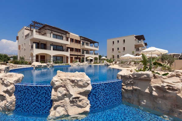Outdoor pool, pool umbrellas, pool loungers - Aphrodite Hills Rentals – Premium Serviced Apartments (Kouklia)