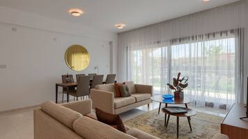 A modern living room with a sofa, coffee table, and dining area.
