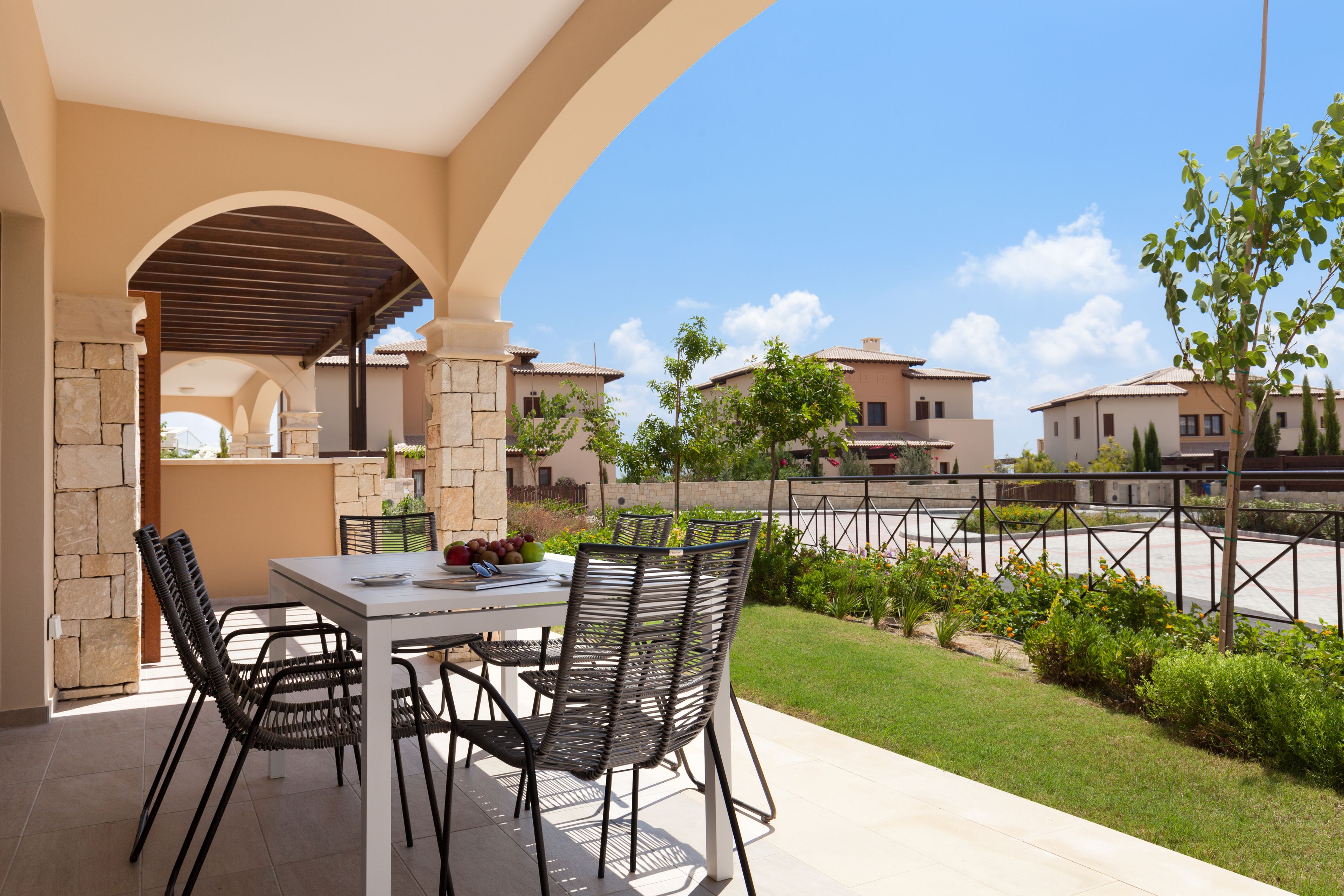 An outdoor patio with a table and chairs, a stone wall, and a view of residential buildings.