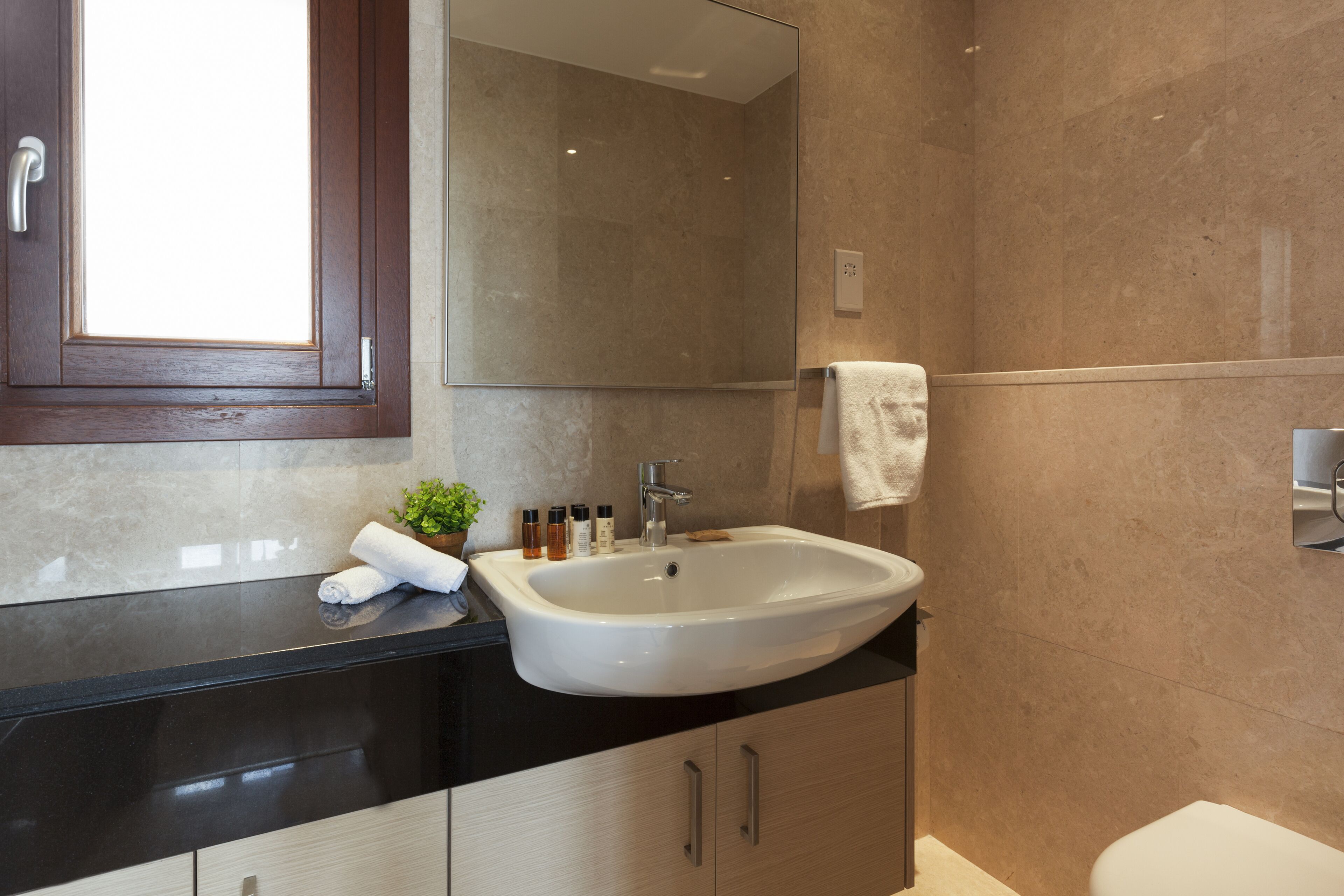 A modern bathroom with a large sink, a mirror, and a toilet.