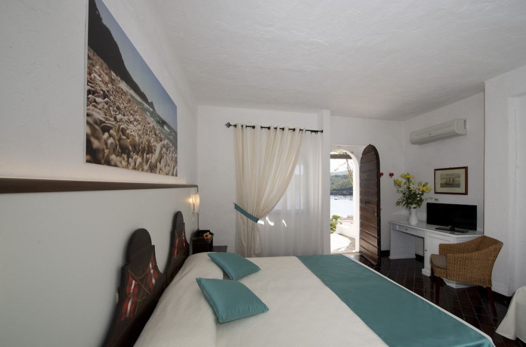 Une chambre d’hôtel avec un lit, un bureau avec une télévision, une chaise et une fenêtre avec des rideaux.