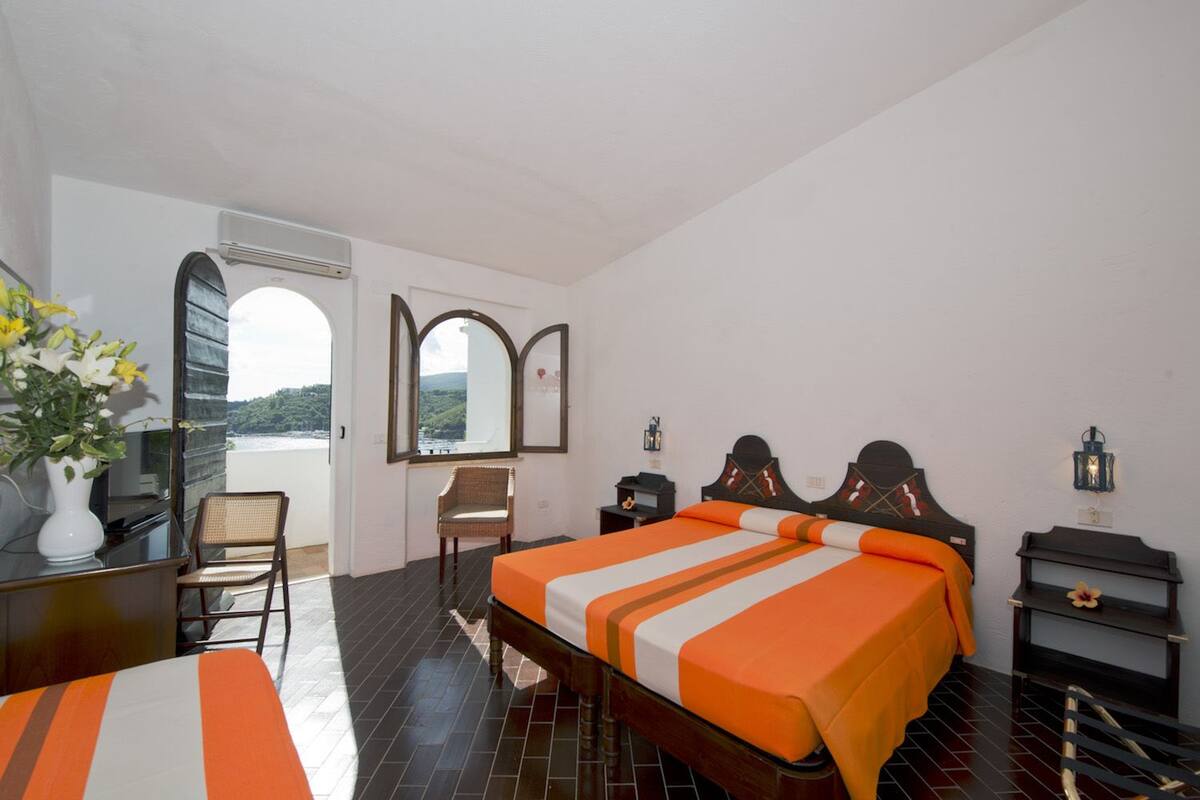 Une chambre à coucher avec un lit, un bureau, une chaise et une vue sur l’extérieur.