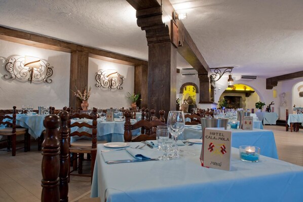Een restaurant met meerdere tafels klaar voor dineren, met een blauwe tafelkleed, houten stoelen en een menukaartstandaard.