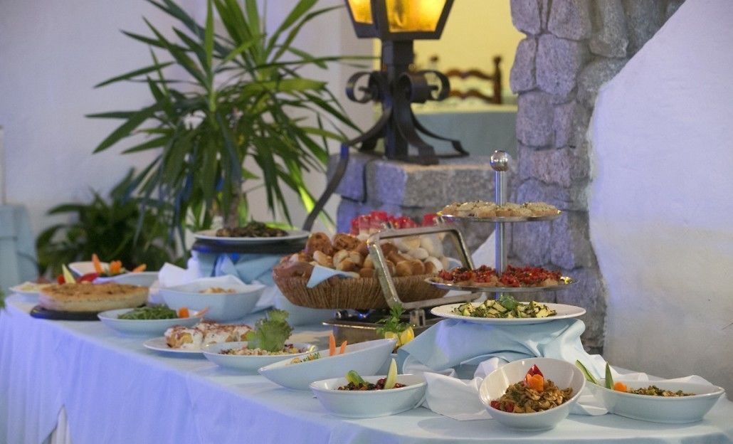 Un tavolo per buffet con diversi piatti e un muro di pietra sullo sfondo.
