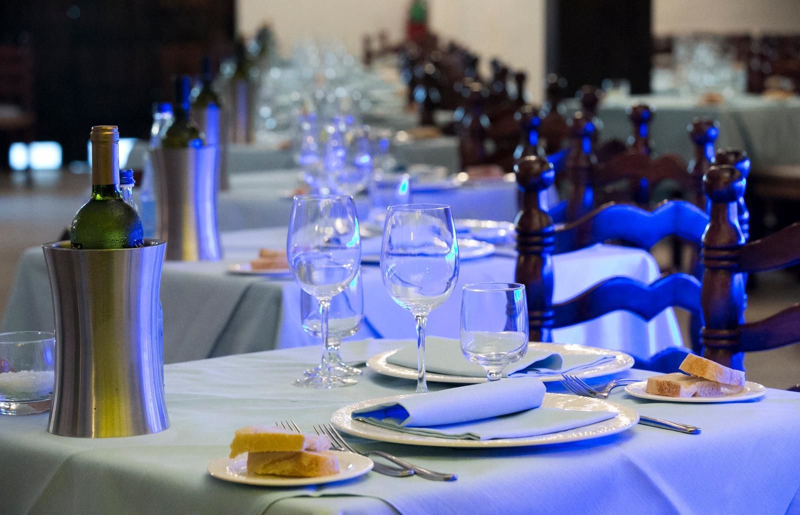 A dining table set with plates, glasses, and cutlery, with a bottle and a napkin on the table.