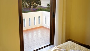 Un dormitorio con cama, vistas al exterior y un balcón.