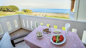 Un balcón con mesa lista para una comida, con vista al mar.