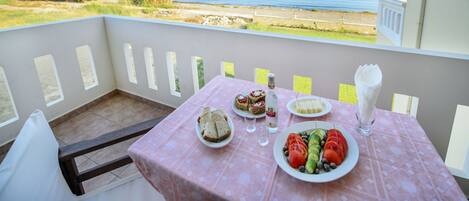Ein Balkon mit Tisch, gedeckt für eine Mahlzeit, mit Blick auf die Küste.