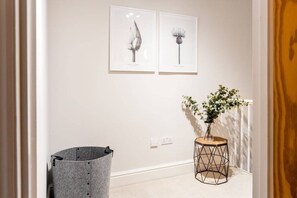 Stylish hallway with a minimalist design, featuring a potted plant and framed botanical illustrations.