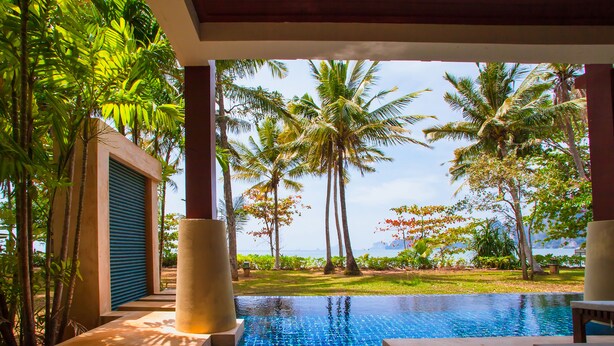 Zona de piscina con vistas a palmeras y una masa de agua.
