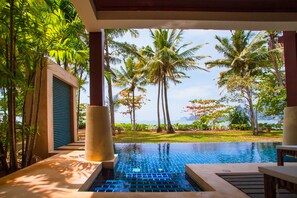 Zona de piscina con vistas a palmeras y una masa de agua.
