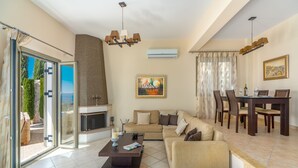 A spacious living room with a sofa, coffee table, and dining area. - Stunning Maisonette close to the sea with breathtaking view and pool (Πόρτο Χέλι)