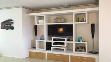 Een moderne woonkamer met een ingebouwde televisie, kasten en opbergladen.