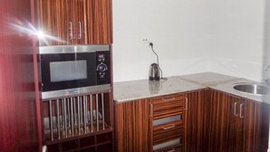 A compact kitchen with a microwave, kettle, and a sink. - Barcelona Apartment (Abuja)
