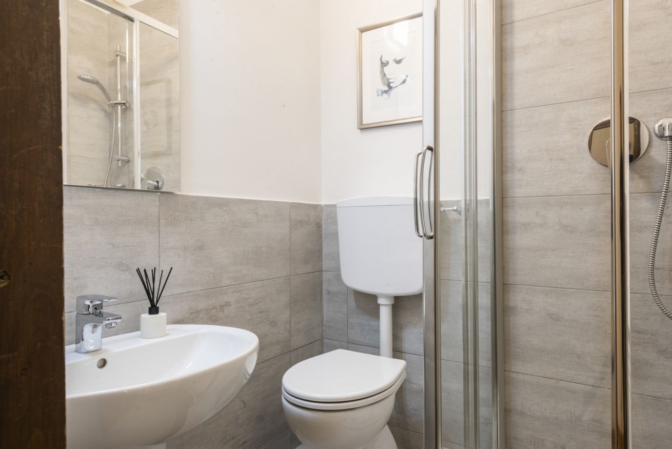 A modern bathroom with a glass shower enclosure, a white toilet, and a sink with a mirror.