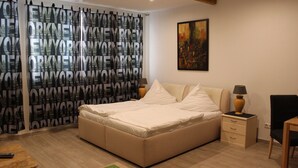 Quarto com uma cama grande, mesa de cabeceira, uma cadeira e um quadro na parede.
