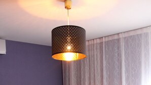 Quarto de hotel moderno com sofá cinzento, cama branca e abajur.
