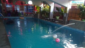 An indoor swimming pool with water jets, a few floating balls, and a poolside area with chairs and a sunbed. - Travel Lodge Sabie (Sabie)