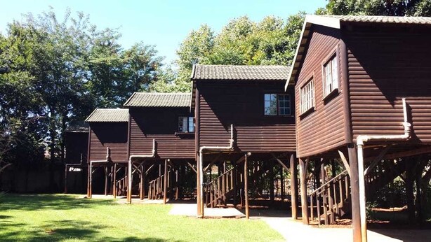 A row of wooden cabins with a simple, rustic design, each with a small window and a door. - Travel Lodge Sabie (Sabie)