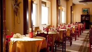 A restaurant with multiple tables set for dining, featuring a warm interior and wooden chairs. - Hotel Cristallo (Spezzano della Sila)